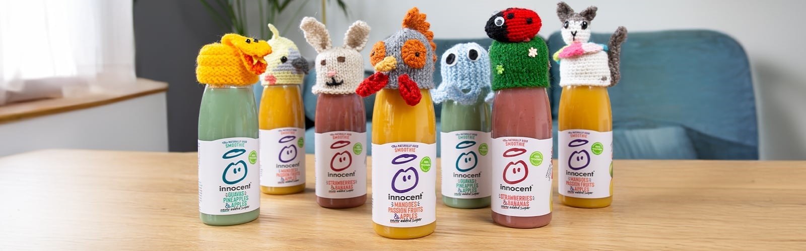 smoothie bottles sitting on a table with small knitted hats over the caps